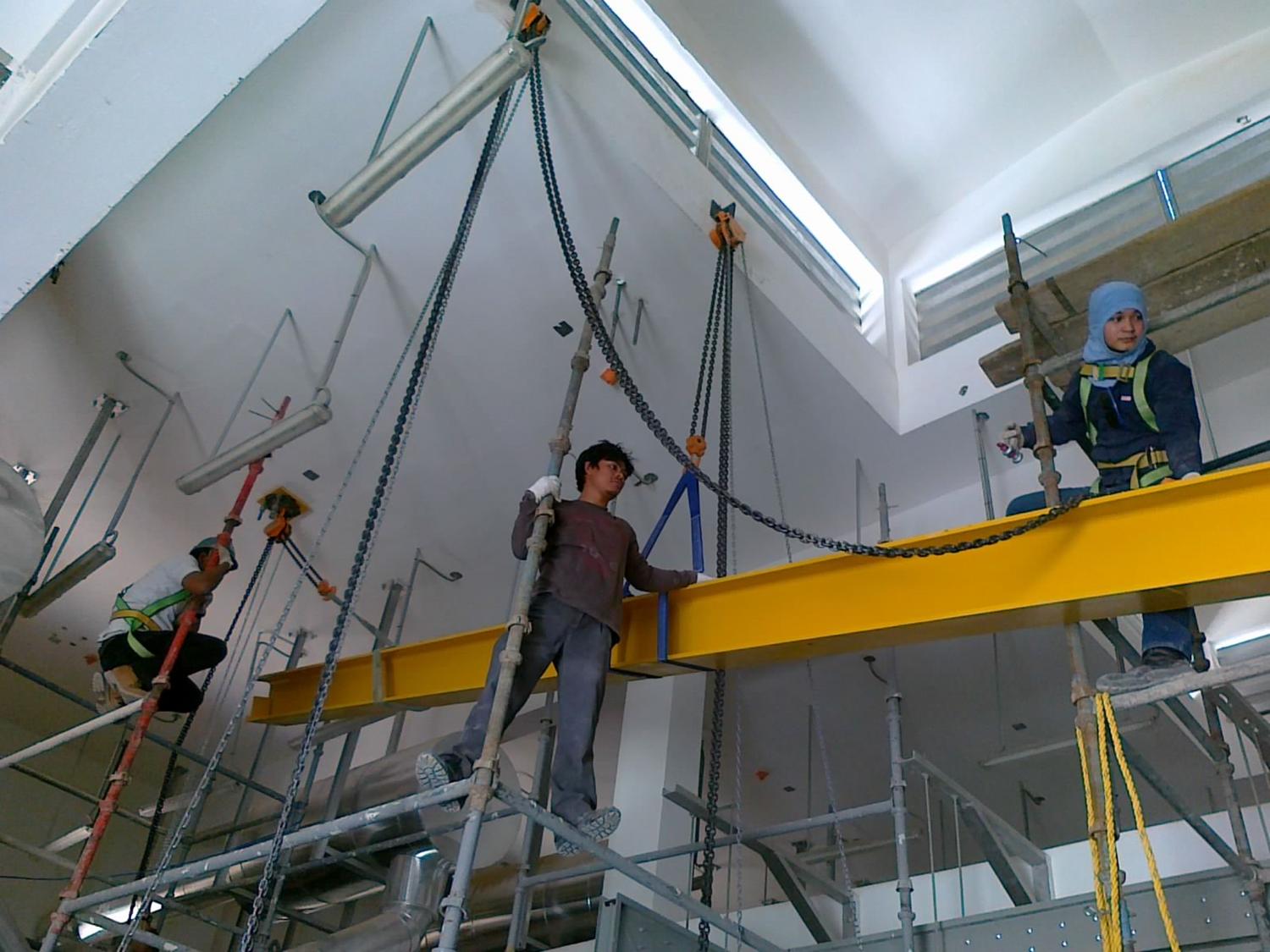 Crew installing a yellow crane runway beam